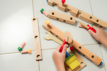 children hands playing with colorful wooden constructor puzzle bricks