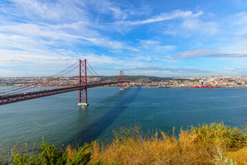 panoramic photo of the cityscape of Lisbon and the 25 April red bridge over the Tagus river on a sunny autumn day