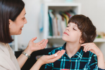 Woman speech therapist helps a boy correct the violation of his speech