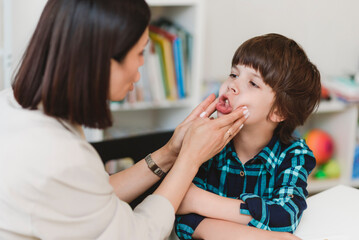 Woman speech therapist helps a boy correct the violation of his speech