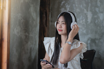 Young woman listening to music from mobile phone at homes, Smiling girl relaxing with headphones.free spare time