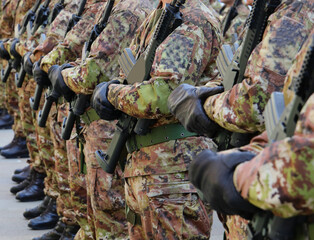 platoon of soldiers with green and brown camouflage uniform with black gloves and assault rifle in...