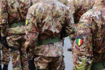 soldiers marching in parade wearing camouflage uniform and crest with national flag with colors...