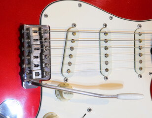 red and white electric guitar with volume knob pickups and a tremolo arm