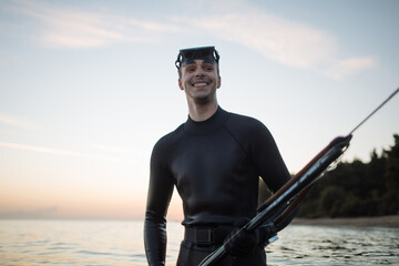 Smiling young spearfisherman posing with mono mask and speargun