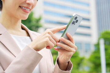 外でスマートフォンを使うビジネスウーマン　顔無し