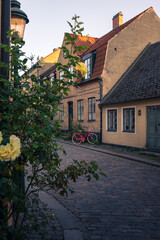 Pink bicycle parked along the facade of town houses in Lund Sweden during summer sunset