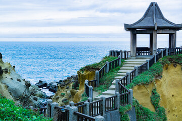 A beach with a stone wall and a stone walkway leading to a pavilion