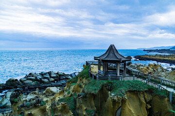 A small hut is on a rocky cliff overlooking the ocean