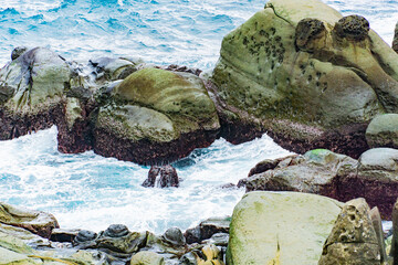 A rocky shoreline with a large boulder in the foreground