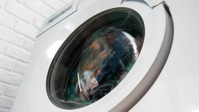 Close-up of a washing machine washing colorful clothes
