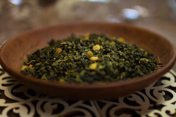 A clay plate with green fruit tea stands on a wooden table.