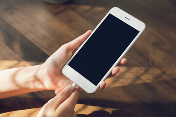 Hand holding smartphone with charge the phone and mockup of blank screen for graphic display...