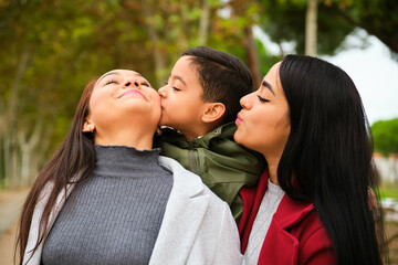 Son kissing his mom, Latin lesbian couple with their son in a park. LGBT family.
