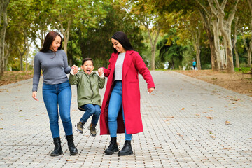 Fototapeta premium Latin lesbian couple playing with their son in a park. LGBT family.