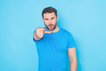 Gesture pointing finger at you. The point you. Happy handsome man pointing finger you away, isolated blue background. Excited man pointing a you great idea. Guy in blue t-shirt pointing finger you.