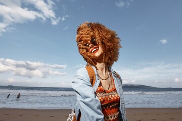 Smiling Woman with Backpack Enjoying a Beach Vacation, Experiencing Freedom and Joy under the Blue Sky