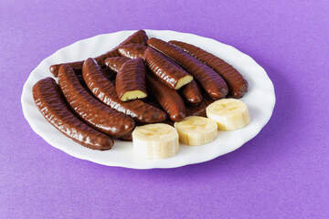 Chocolate covered banana flavored slices on a plate on a purple background