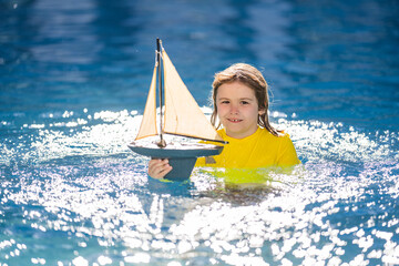 Kid play with toy sailing boat. Summer travel, kids holidays. Journey trip lifestyle yachting...