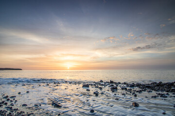 Sunrise with sea view in a secluded bay. rocky coast in warm colors. Landscape with a lava stone beach at Tarajalejo on Fuerteventura, Canary Islands, Spain.