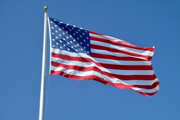 Obraz premium Flag of United States of America being waved in the breeze against a sky. USA flag