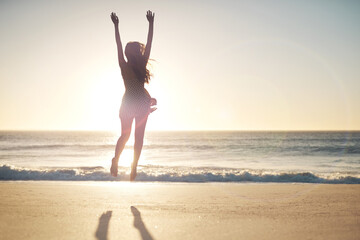 Woman, jump and success with freedom at beach with sunset sky, mockup space and celebration. Girl,...