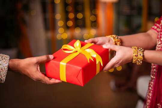 Indian asian woman wears gold bangles on festival day receiving gift box. closeup picture