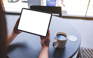 Mockup image of a woman holding digital tablet with blank white desktop screen in cafe