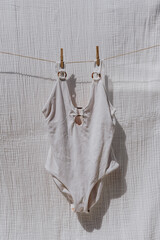 Female swimsuit hanging on rope over muslin cloth with sunlight