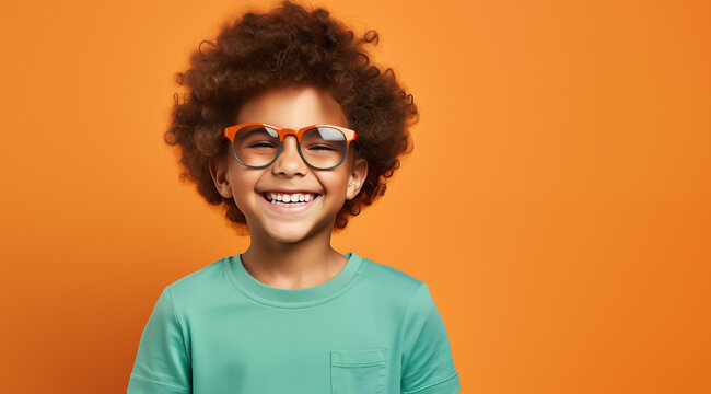 Un enfant noir, heureux et souriant &acirc;g&eacute; de 10 ans, portant des lunettes et un tee-shirt vert, arri&egrave;re-plan isol&eacute;, color&eacute;, orange, image avec espace pour texte.