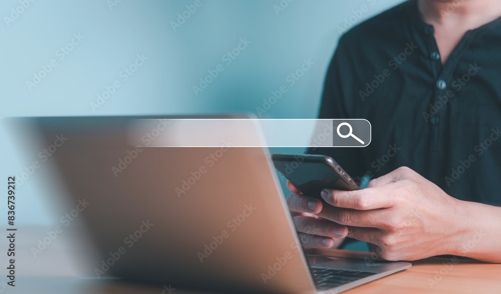 Aufkleber a person holding a smartphone while using a laptop, symbolizing online search and multitasking in a 