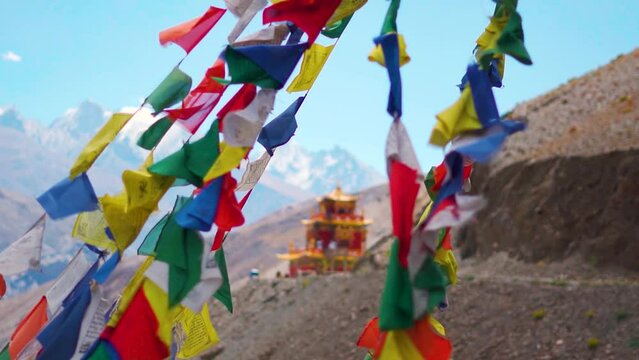 Slow motion shot of colorful Tibetan Buddhist prayer flags waving in front of the Gue Monastery in Spiti Valley, Himachal Pradesh, India. Prayer flags in front of the monastery in India.