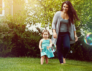 Mom, girl and happy with bubbles in garden for games, running or playful with bonding at family house. Child, mother and daughter with soap, smile or care with love for connection on lawn in backyard