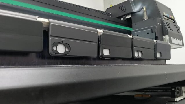 A modern digital large-format UV printer prints images on smartphone cases. UV pinning is the process of applying a dose of low intensity ultraviolet light to a UV curable ink