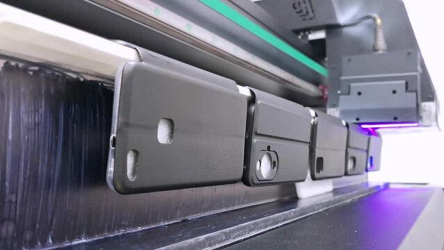 A modern digital large-format UV printer prints images on smartphone cases. UV pinning is the process of applying a dose of low intensity ultraviolet light to a UV curable ink
