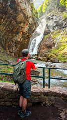 Wonders of the Pyrenees: A boy contemplates one of the waterfalls on the Cola de Caballo trail in Ordesa and Monte Perdido National Park, surrounded by high mountains and the Arazas River in Huesca.