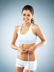 Stomach, portrait or happy woman with tape measure for fitness, body progress or workout in studio. Girl, smile or proud athlete with exercise, wellness or training to lose weight on blue background