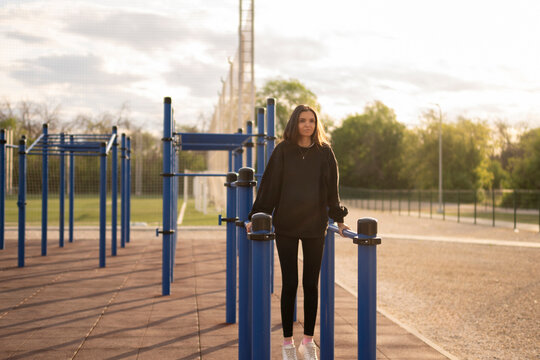 Woman Working Out on Parallel Bars at outdoor Public Park during sunset