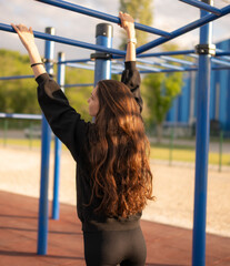 Woman Doing sport Pull-Ups on Monkey Bars at Outdoor Gym