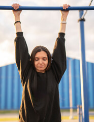 Fototapeta premium Woman Doing a Leg Raise Exercise on a Horizontal Bar at an Outdoor Workout Area