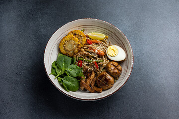 Asian cuisine. Noodles with egg and corn in a plate. On a dark background