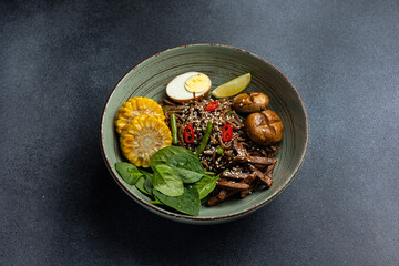 Asian cuisine. Noodles with egg and corn in a plate. On a dark background