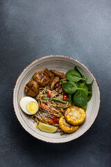 Asian cuisine. Noodles with egg and corn in a plate. On a dark background
