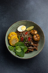 Asian cuisine. Noodles with egg and corn in a plate. On a dark background