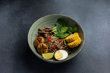 Asian cuisine. Noodles with egg and corn in a plate. On a dark background