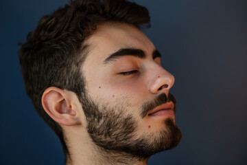 Obraz premium A close up of a man with beard and closed eyes looking to a side