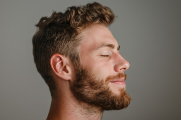 Obraz premium A close up of a man with beard and closed eyes looking to a side