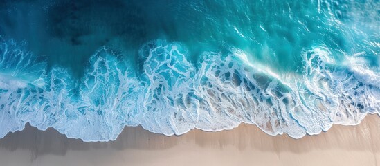 Blue waves are seen rolling towards the shore of a sunny beach, merging with the pristine white sand. The ocean's waves bring dynamic movement to the otherwise tranquil and serene background