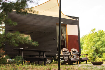 A modular frame-type apartment on wheels, lined with wood against the background of an autumn forest.