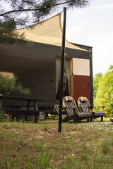 A modular frame-type apartment on wheels, lined with wood against the background of an autumn forest.